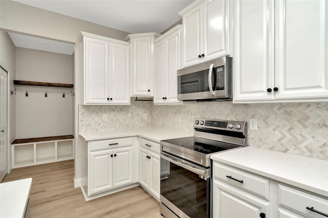 kitchen featuring light wood finished floors, appliances with stainless steel finishes, white cabinets, and tasteful backsplash