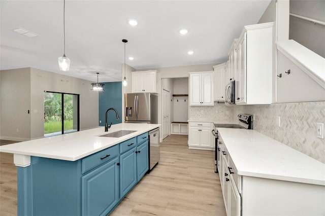 kitchen with blue cabinetry, appliances with stainless steel finishes, a sink, white cabinets, and light wood-style flooring