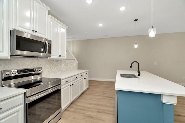 kitchen with light wood-type flooring, white cabinets, tasteful backsplash, a sink, and appliances with stainless steel finishes