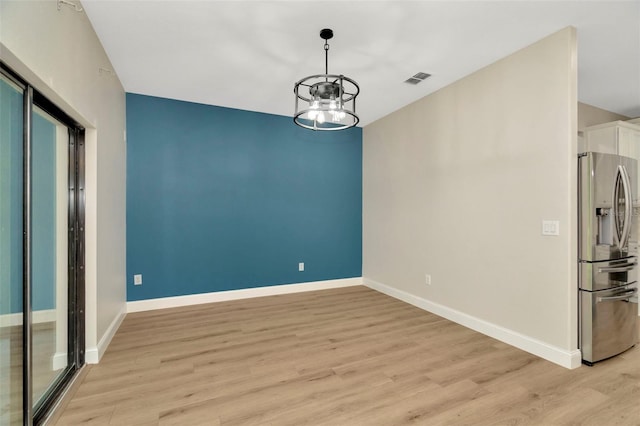 unfurnished dining area with an inviting chandelier, baseboards, light wood-style flooring, and visible vents