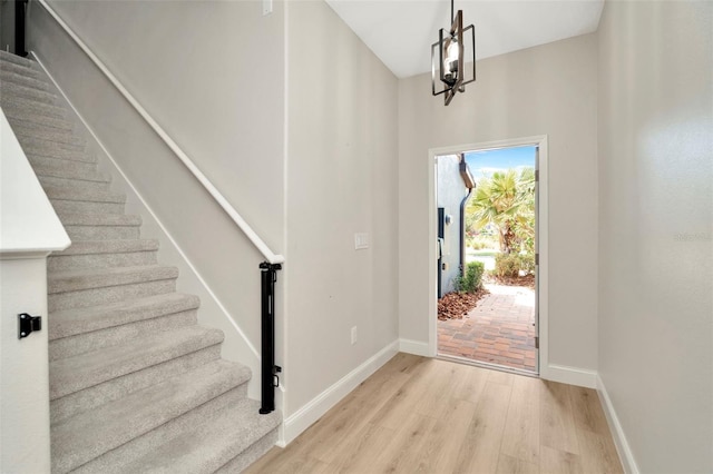 foyer featuring baseboards, light wood finished floors, and stairs