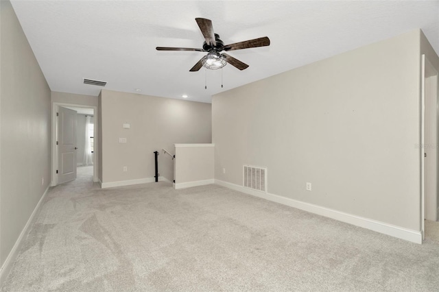 unfurnished room featuring a ceiling fan, baseboards, light colored carpet, and visible vents