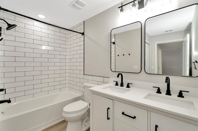 bathroom featuring toilet, visible vents, a sink, and shower / washtub combination