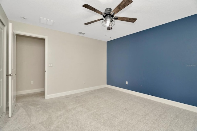 unfurnished bedroom featuring light colored carpet, baseboards, visible vents, and a ceiling fan