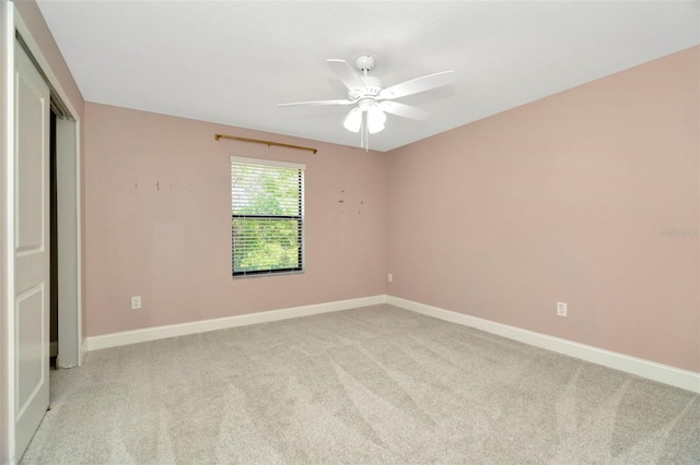 spare room with baseboards, light carpet, and a ceiling fan