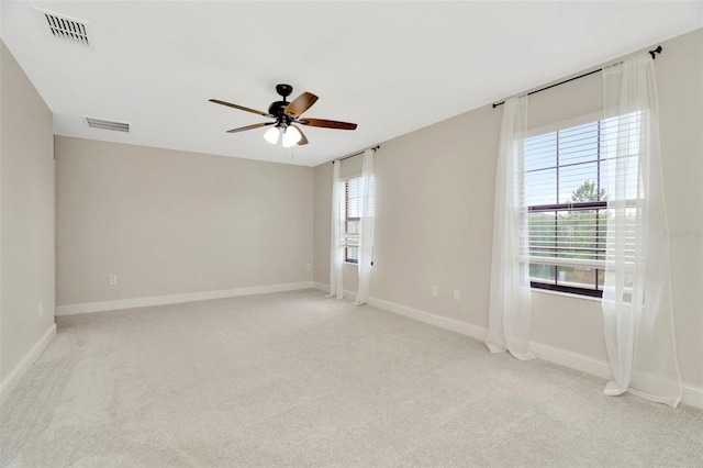 spare room featuring ceiling fan, light colored carpet, and visible vents