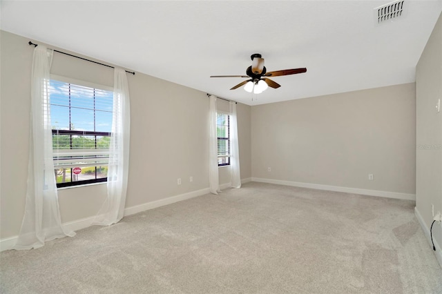 unfurnished room featuring a ceiling fan, baseboards, light colored carpet, and visible vents