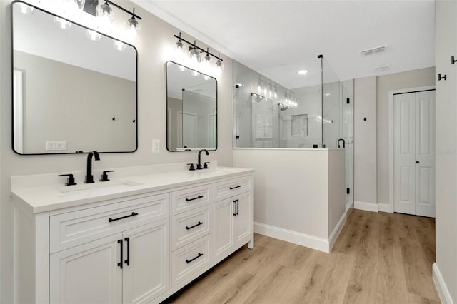 full bathroom with a sink, baseboards, a shower stall, and wood finished floors