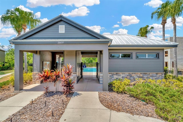 view of front of property with fence, metal roof, a gate, and stone siding