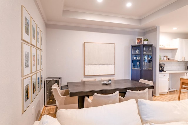 dining area featuring crown molding, a tray ceiling, and light wood finished floors