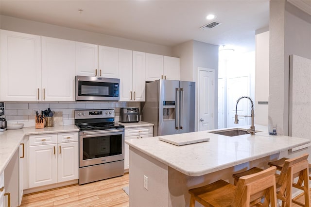 kitchen featuring white cabinets, stainless steel appliances, visible vents, and a sink