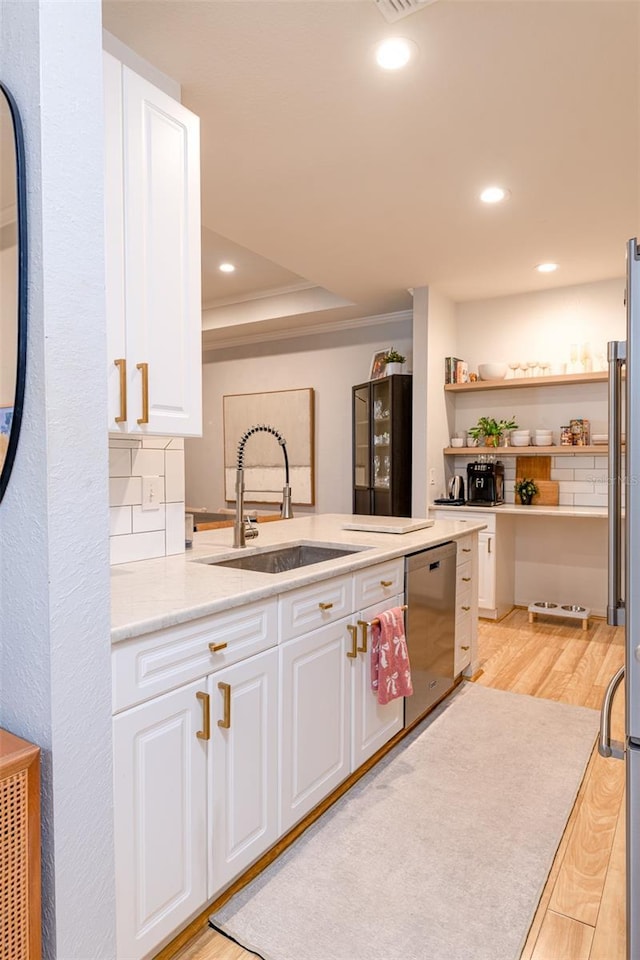 kitchen with stainless steel appliances, white cabinetry, a sink, and light wood finished floors