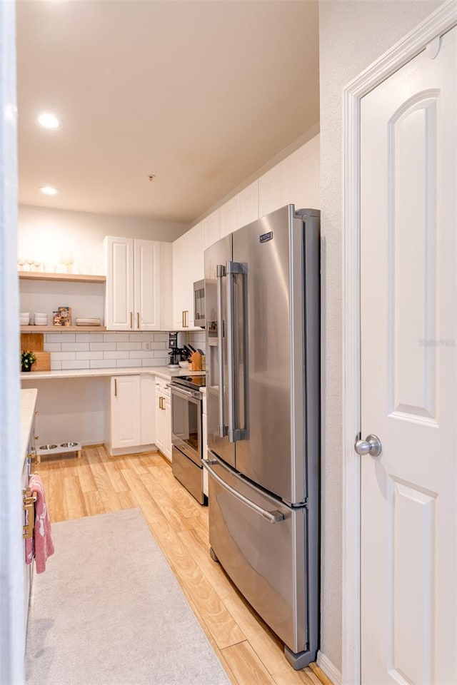 kitchen featuring light wood-type flooring, light countertops, appliances with stainless steel finishes, and white cabinets