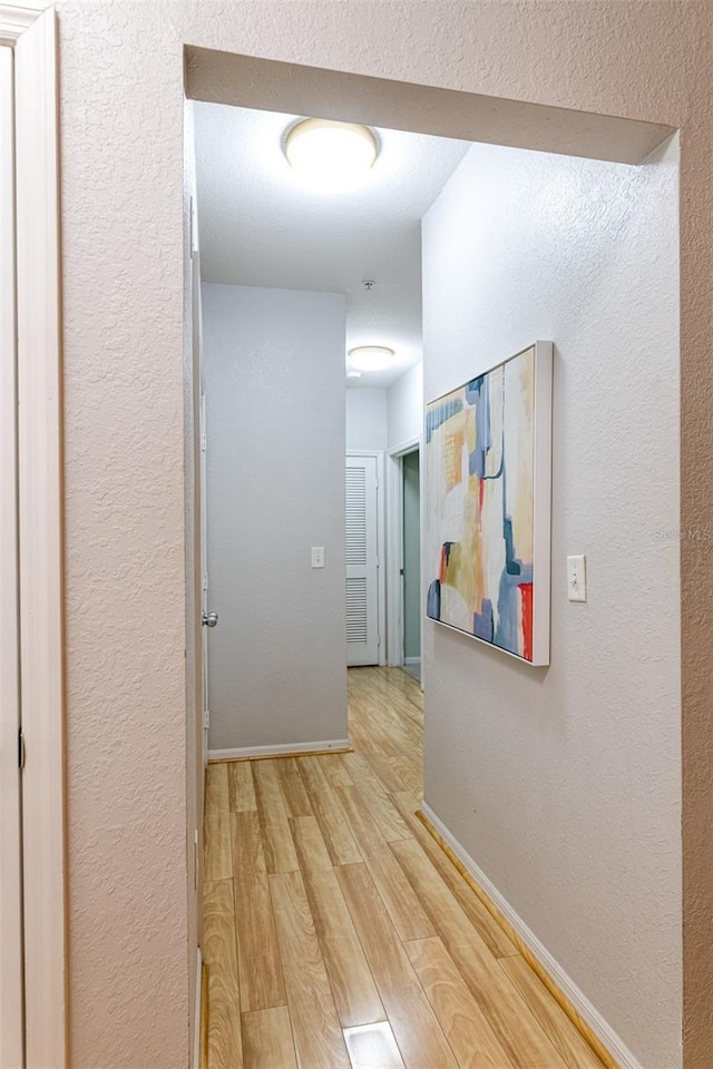 hall featuring baseboards and light wood finished floors