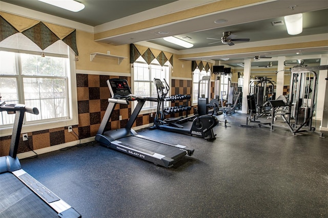 gym featuring a ceiling fan, wainscoting, and wallpapered walls