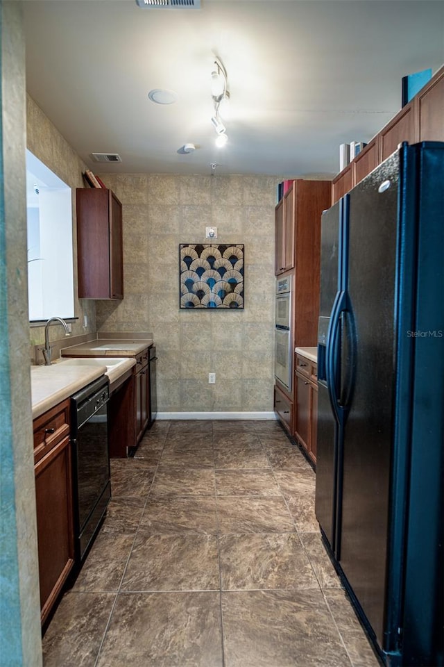 kitchen featuring visible vents, light countertops, a sink, and black appliances
