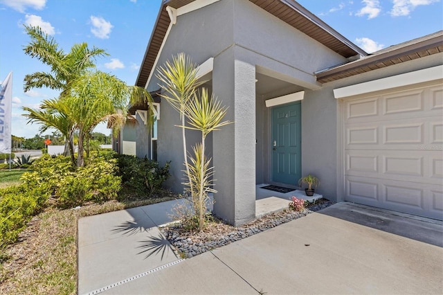 property entrance with an attached garage, stucco siding, and concrete driveway