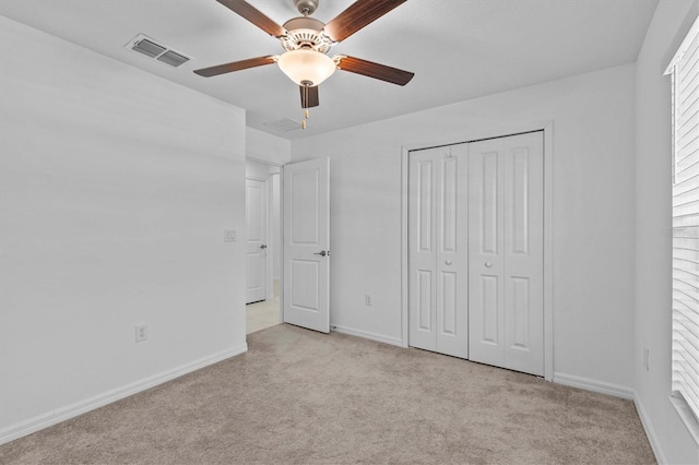 unfurnished bedroom featuring ceiling fan, visible vents, baseboards, a closet, and light carpet