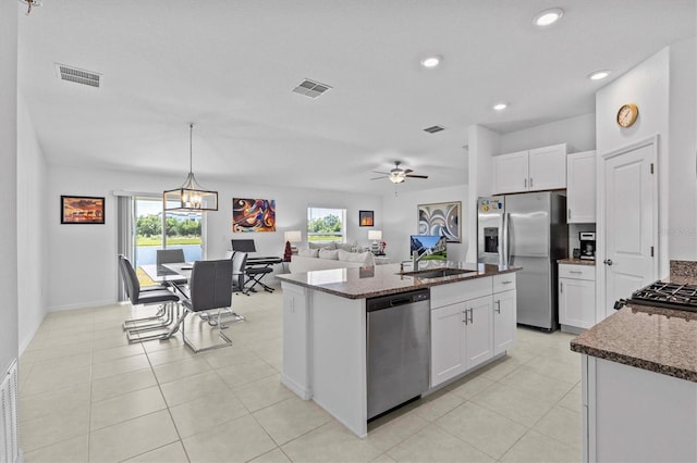 kitchen with visible vents, white cabinets, a sink, dark stone countertops, and appliances with stainless steel finishes