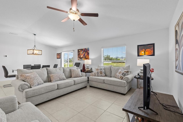 living area with light tile patterned flooring, vaulted ceiling, and ceiling fan with notable chandelier