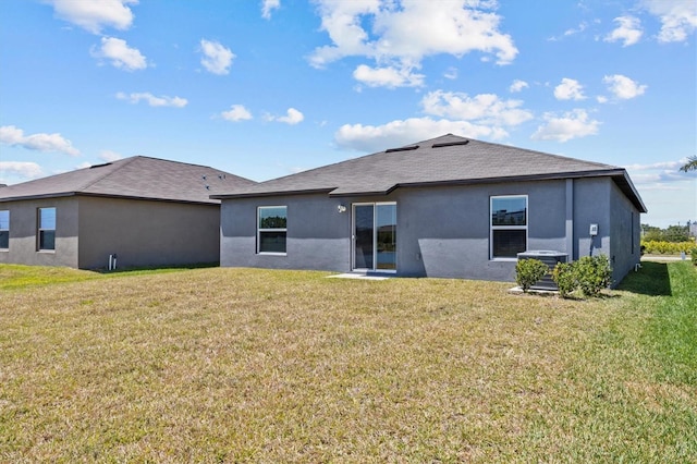 back of property with a lawn, central AC unit, and stucco siding