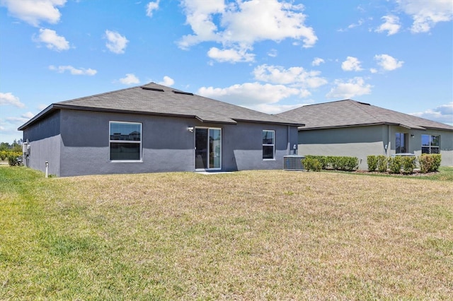 back of property with central AC, a shingled roof, stucco siding, and a yard