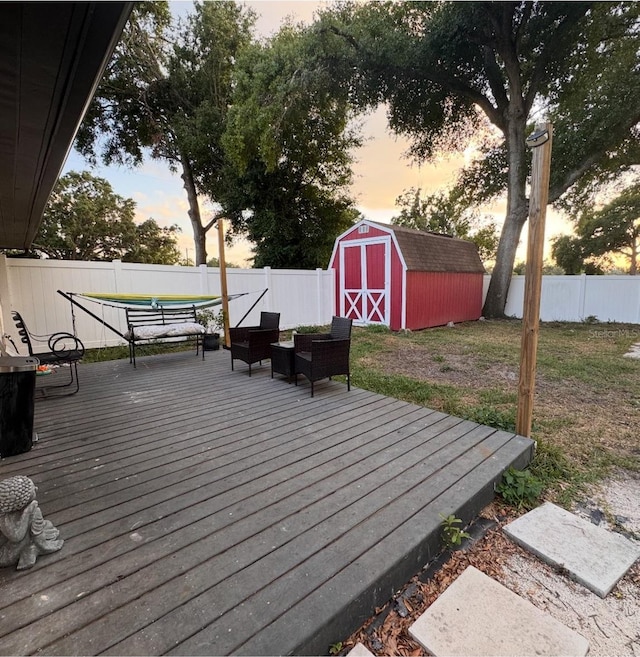 wooden terrace with a lawn, a fenced backyard, a shed, and an outbuilding