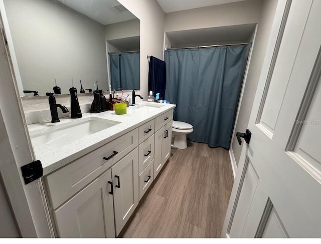 bathroom with double vanity, a sink, wood finished floors, and visible vents