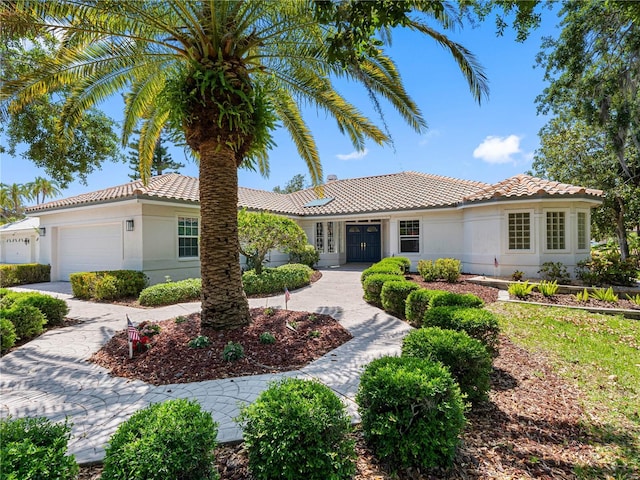 view of front of property featuring stucco siding, french doors, a garage, and a tiled roof