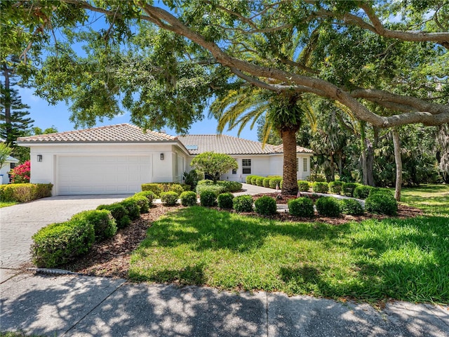 ranch-style house featuring a tiled roof, decorative driveway, stucco siding, and a garage