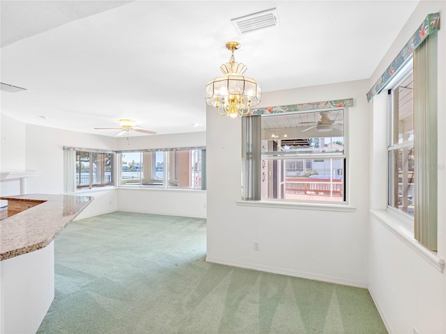 unfurnished dining area featuring visible vents, carpet floors, and ceiling fan with notable chandelier