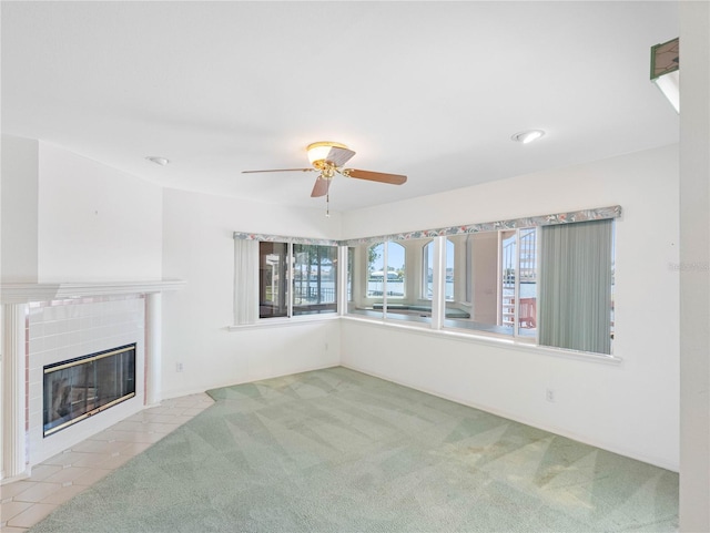 unfurnished living room featuring ceiling fan, carpet floors, plenty of natural light, and a tile fireplace