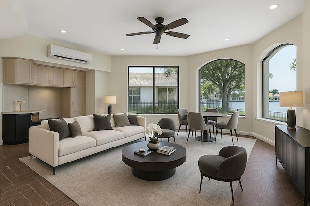 living room featuring a ceiling fan, recessed lighting, a wall unit AC, baseboards, and a water view