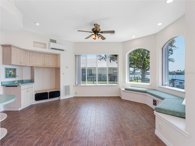 interior space with visible vents, a wall mounted AC, a healthy amount of sunlight, and a sink
