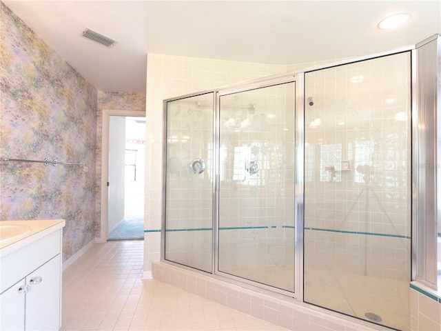 bathroom featuring vanity, visible vents, tile patterned floors, a shower stall, and baseboards