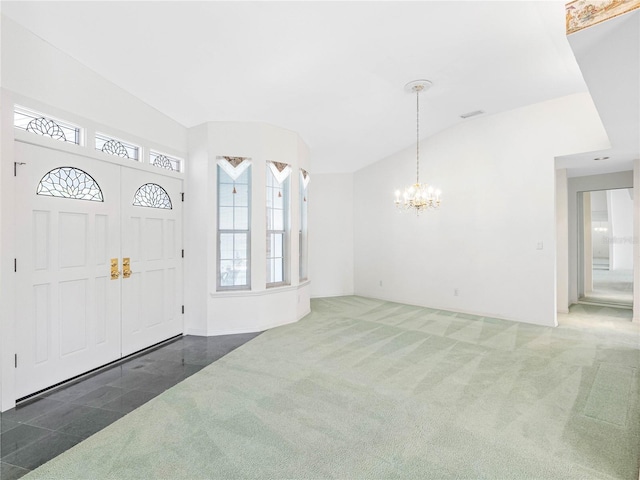 carpeted foyer featuring an inviting chandelier and plenty of natural light