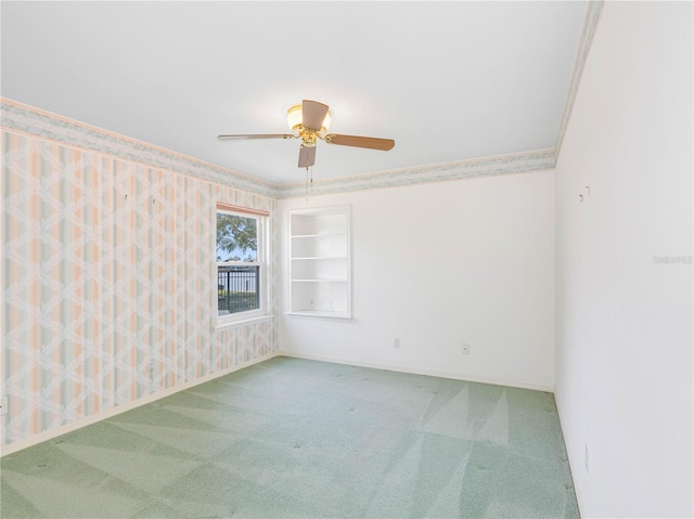 carpeted spare room featuring ceiling fan and baseboards