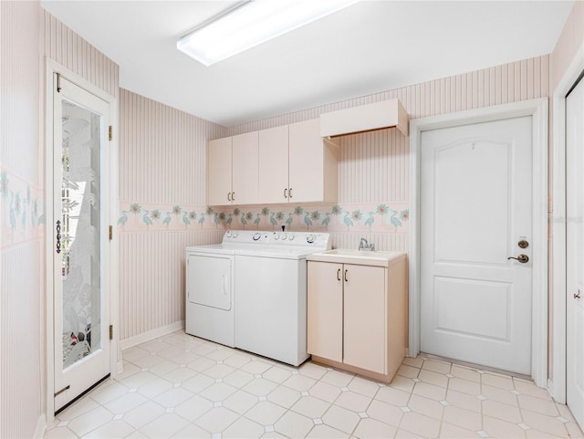 clothes washing area with cabinet space, wallpapered walls, light floors, and washing machine and clothes dryer