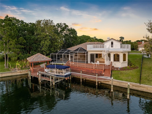 dock area with a gazebo, a water view, a lawn, and a balcony