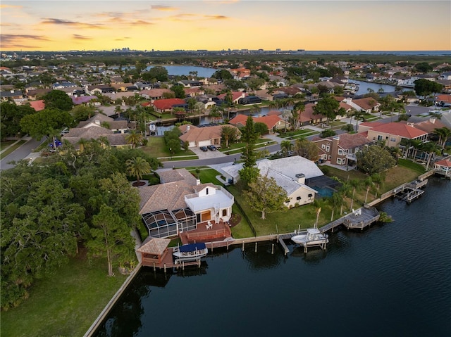 aerial view at dusk featuring a water view and a residential view