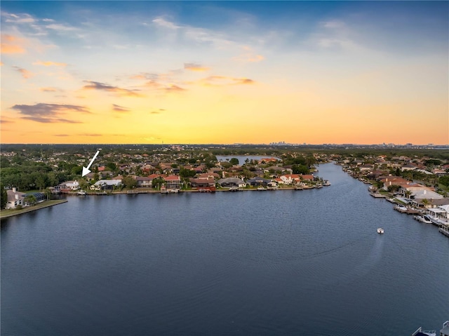 aerial view at dusk with a water view and a residential view