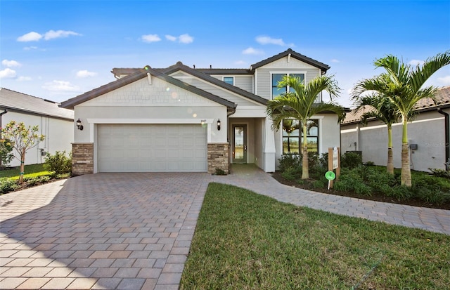 5949 Bluestar Ct, Lakewood Ranch, FL 34211 - view of front of home with stone siding, a garage, stucco siding, a front yard, and decorative driveway