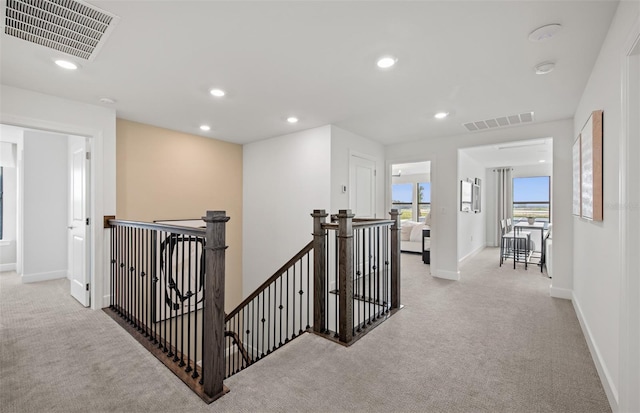 5949 Bluestar Ct, Lakewood Ranch, FL 34211 - hallway with visible vents, light carpet, and an upstairs landing