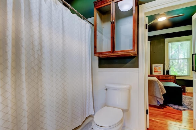 6341 Discovery Ln, Land O Lakes, FL 34638 - full bath featuring connected bathroom, a wainscoted wall, wood finished floors, toilet, and curtained shower