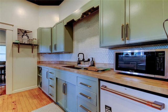 6341 Discovery Ln, Land O Lakes, FL 34638 - kitchen featuring butcher block countertops, stainless steel microwave, decorative backsplash, light wood finished floors, and a sink