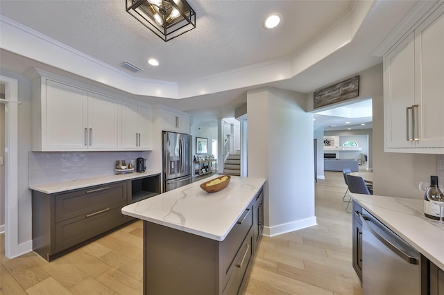 945 Bunker View Dr, Apollo Beach, FL 33572 - kitchen with light stone counters, a raised ceiling, stainless steel appliances, tasteful backsplash, and visible vents