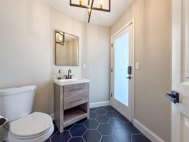 945 Bunker View Dr, Apollo Beach, FL 33572 - half bathroom featuring an inviting chandelier, tile patterned flooring, vanity, toilet, and baseboards