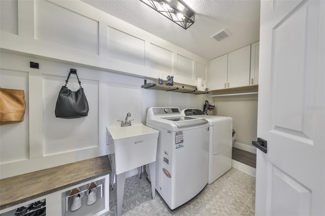 945 Bunker View Dr, Apollo Beach, FL 33572 - laundry room with cabinet space, a sink, separate washer and dryer, a textured ceiling, and visible vents