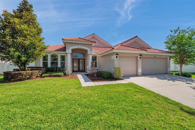 mediterranean / spanish home featuring an attached garage, stucco siding, french doors, a tiled roof, and driveway