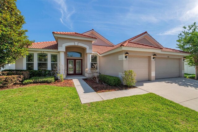 mediterranean / spanish-style home with a garage, a front lawn, stucco siding, french doors, and a tiled roof